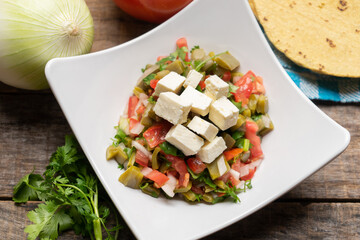 Nopal cactus salad with cheese on wooden background. Mexican food