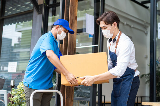 Asian Postman delivery in blue uniform deliver food box to restaurant.