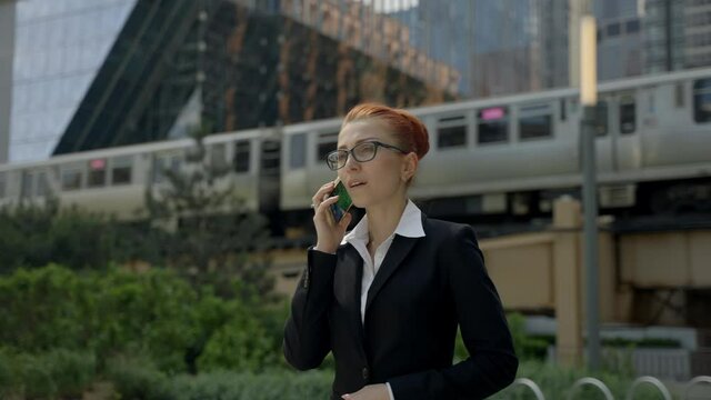 Young business woman with ginger red hair talking on mobile phone in down town.