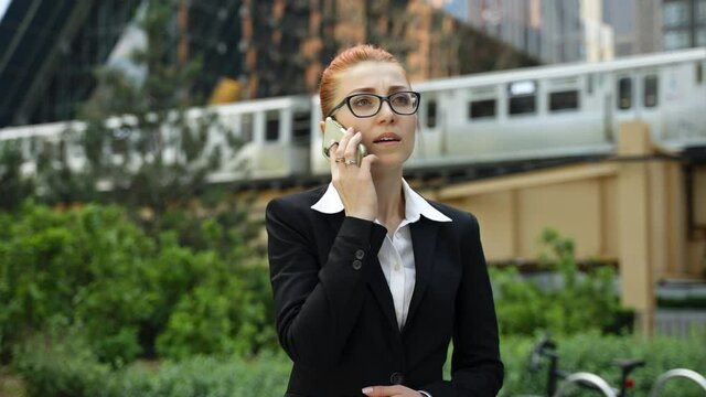 Young business woman with ginger red hair talking on mobile phone in down town.
