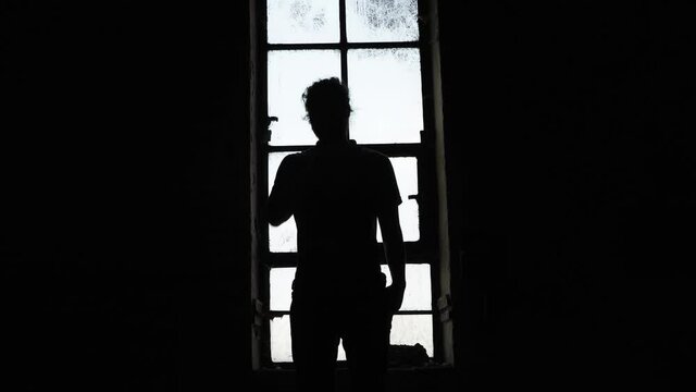 A man standing in a window in silhouette.
