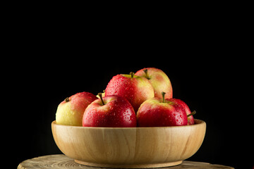 Close up Apples in a wooden bowl on black background
