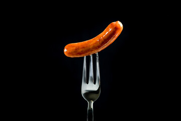Sausage, prick with a fork. Object on a black background