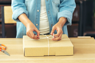Woman packing box on table checking goods package delivery shipping to customer. Asian woman startup small business at home office desk. Entrepreneur asian woman packing product for delivery items