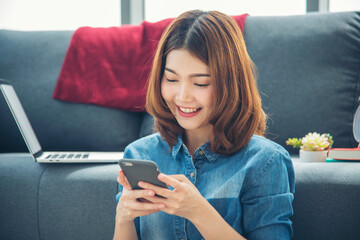 Smiling face asian woman holding smartphone with E-commerce Shopping online website Reading Online...
