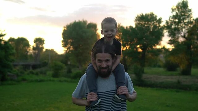 summer, vacation, nature, happy family, childhood, paternity, father Day - Dad with preschool child son boy kid run playing plane spread arms wings have fun sit on shoulder in park meadow at sunset