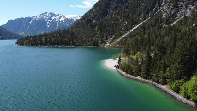 Hiking trail alongside the beautiful lake Achen. Beautiful mountains around and peaks covered with snow. Drone, aerial view of alpine nature.