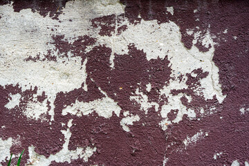 An old concrete wall with peeling paint patches, the surface damaged by time and weather