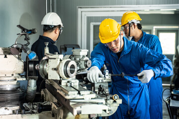 Asian technician mechanical worker work on milling machine in factory.