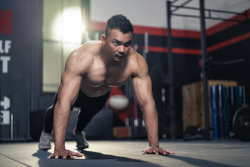 Fototapeta na wymiar Asian strong muscular sportsman exercise, push up on floor in stadium.