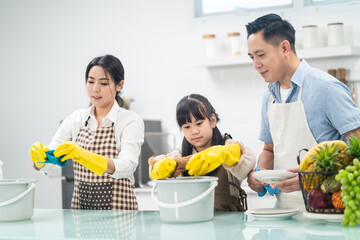 Asian happy family, parents teach young daughter clean kitchen at home