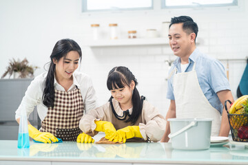 Asian happy family, parents teach young daughter clean kitchen at home