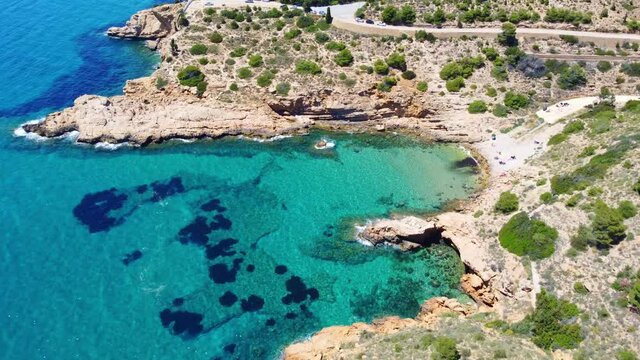 Rocky Cove Of Cala Tio Ximo Beach And Cova del Barber By Clear And Calm Water Of Mediterranean Sea - Tourist Attraction At Benidorm, Alicante, Spain. - aerial