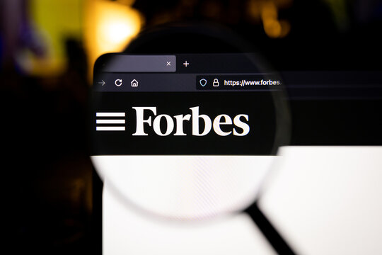 Forbes company logo on a website, seen on a computer screen through a magnifying glass.