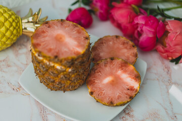 sliced pink pineapple on a plate with peonies