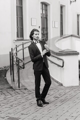 Handsome fashion businessman model dressed in elegant suit and posing on street. Metrosexual