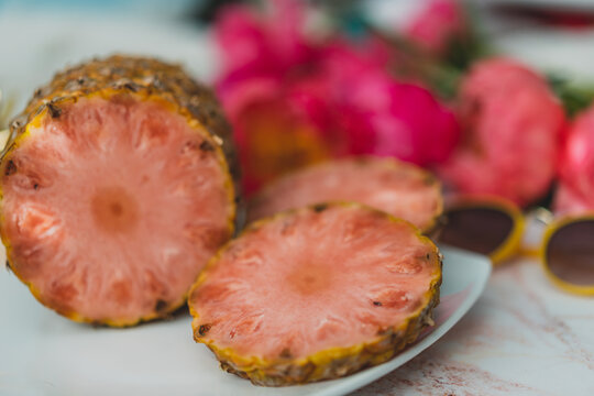 pink pineapple on a plate with flowers in the background