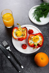 Fried eggs in red peppr on a white plate and dark grey table.