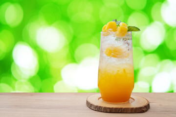 A glass of orange juice on wooden table isolated on green blurred background. summer cocktails, healthy drinking concept.