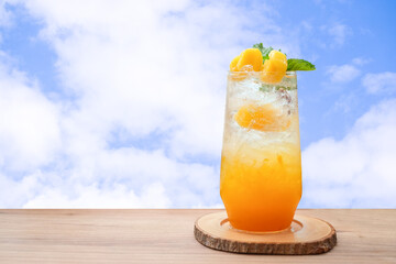 A glass of orange juice on wooden table isolated on blue sky background. summer cocktails, healthy drinking concept.