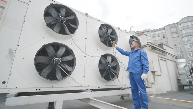 Technician uses a thermal imaging infrared thermometer to check the condensing unit heat exchanger