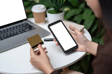 Close-up of a woman sitting at a café holding a smartphone white screen and credit card online shopping.