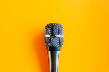 Microphone on a colorful orange background close up. Singing, writing music, karaoke online, creativity, vocals concept, symbol. Singing lessons