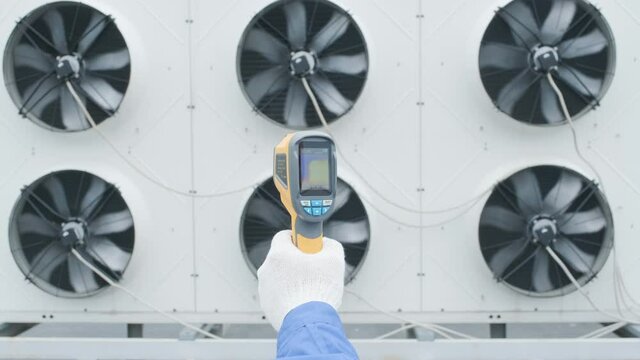 Technician uses a thermal imaging infrared thermometer to check the condensing unit heat exchanger