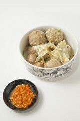 Indonesian meatball served with soup and dumplings, with chili sauce, on white background 