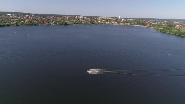 Aerial view of city beach on the outskirts of a small provincial town and people ride a jetski on the city pond. Summer sunny day
