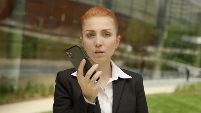 Young business woman with ginger red hair hangs up the phone and looking in the camera with sad face.
