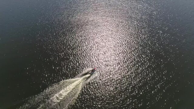 Aerial view of man ride a red and whitejetski on the city pond. Summer sunny day
