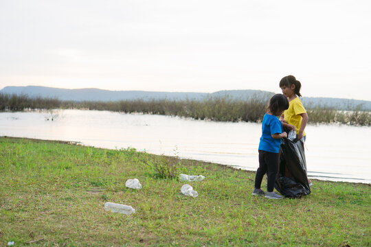 Cute girl while helping sibling to clean up garbage - Powered by Adobe