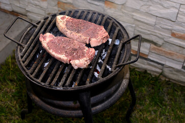 Marinated meat roasting on a grill in a home patio.
