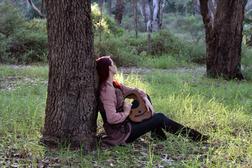 portrait of red haired girl wearing fantasy medieval clothes of a wandering adventurer.  natural light in a woodland forest setting.