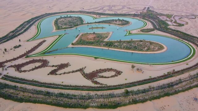Stunning Aerial View Of Love Lake And Sand Desert In Al Qudra Oasis, Dubai. Heat-shaped Lake In UAE. drone pullback
