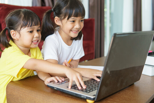 Two Asian Child Girl Students Study Online With Teacher By Video Call Together. Siblings Are Homeschooling With Computer Laptop During Quarantine Due To Covid 19 Pandemic.