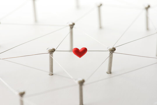 Linking entities. Network, networking, social media, internet communication abstract. Online love or matching. Web of silver wires isolated on natural white, with one connection having a red heart.