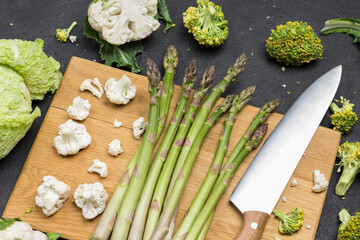 Kitchen knife and asparagus on cutting board.