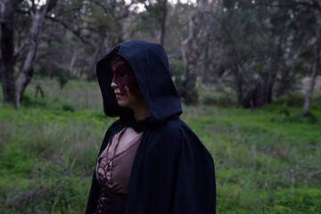 portrait of red haired girl wearing fantasy medieval clothes of a wandering adventurer.  natural light in a woodland forest setting.