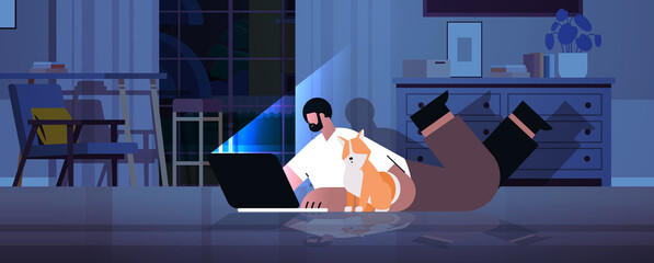 overworked businessman freelancer looking at laptop screen man with dog lying on floor in dark night home room