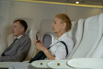 Passenger elderly woman seated on the plane in flight,Travel concept.