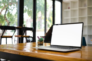 Mock up laptop computer with empty display on wooden table.