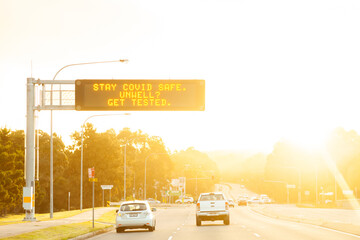 Stay covid safe, unwell, get tested - digital sign above road