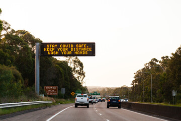 Digital sign above road warning about covid-19 safety Stay covid safe Keep your distance wash hands