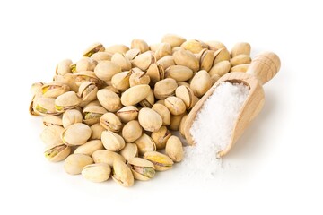 Heap of salted, roasted green pistachio nuts snack over white background with sea salt in wooden scoop, healthy food snack