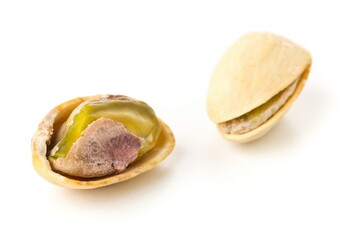 Macro of single salted, roasted green pistachio nut over white background, healthy food snack