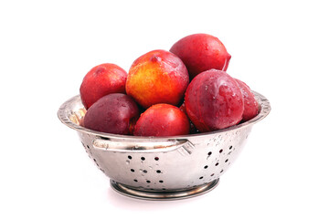 Fresh ripe nectarines in steel colander isolated on white background. Water drops on washed nectarines.