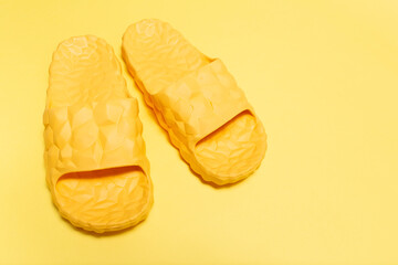 Close-up view of yellow slippers on yellow background.
