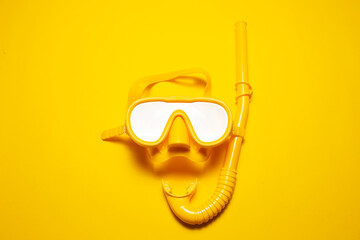 Studio shot yellow diving mask with snorkel, part of dive equipment isolated on yellow background.